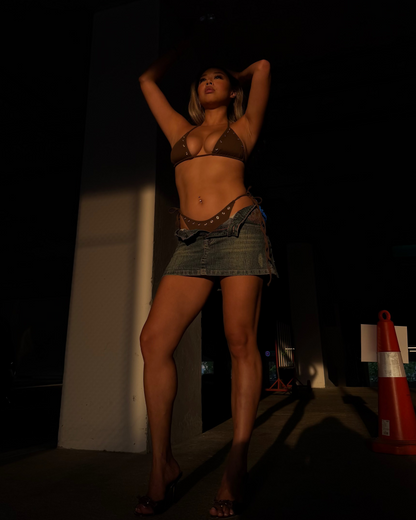 Brown bikini with stud detailing in golden hour posing in a dark setting with a traffic cone in the background
